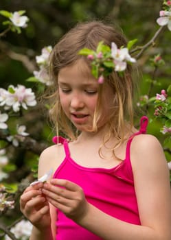 Portrait of a blonde girl in front of apple blossoms