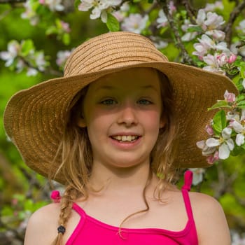 Portrait of a blonde girl in front of apple blossoms