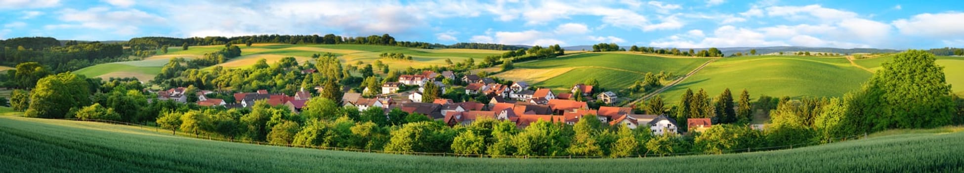 Super wide panorama of a small German village surrounded by green landscaped hills