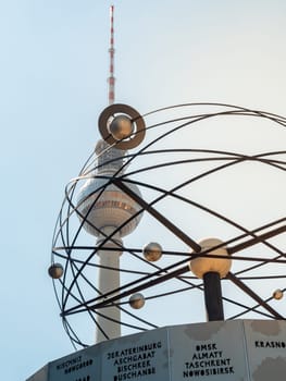 Famous Berlin Television Tower, observation Tower with world clock and plantes sculpture in front, view from low angle during sunset, clear sky