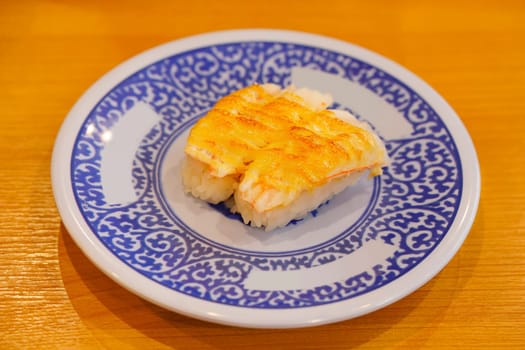 Close-up on Japanese shrimp sushi grilled with cheese.