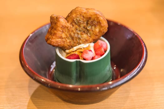 Japanese fish-shaped sweet Taiyaki with red beans or custard paste inside and strawberries on vanilla ice in a bamboo shaped cup.