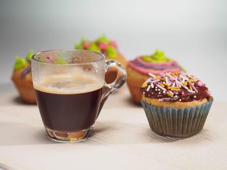 Muffins with colorful decoration and coffee on white table