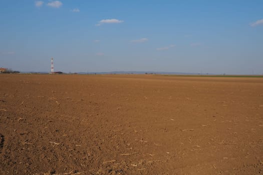 Arable field ready for spring agricultural work. Furrows from the passage of a tractor or combine. Cornmeal on the ground. Fertile soil for planting. Fertilizers are the key to a good harvest