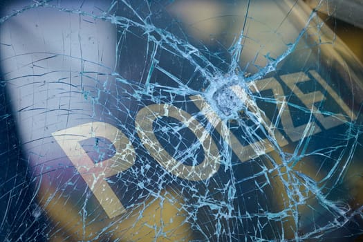 Broken glass and a police car as a symbol of violence against the police