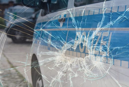 Broken glass and a police car as a symbol of violence against the police