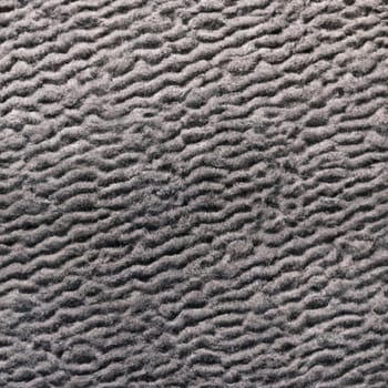 Beige brown pale pastel knitted fabric. Gray-black astrakhan fur. Shaggy weave. Textile, thick fabric. Stretch jersey. Light textile industry. Material sample
