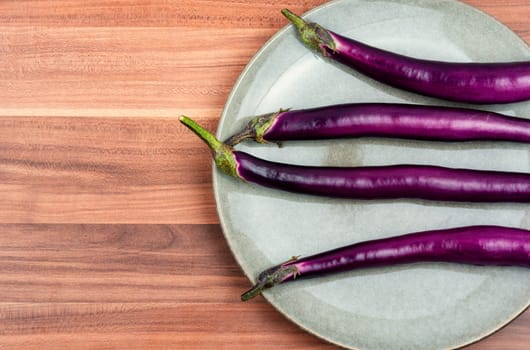 Raw small eggplants on the kitchen table. Diet menu concept. Flat lay