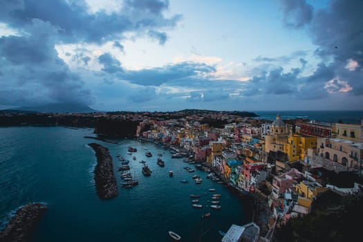 View of the Port of Corricella with lots of colorful houses after sunset in Procida Island, Italy.