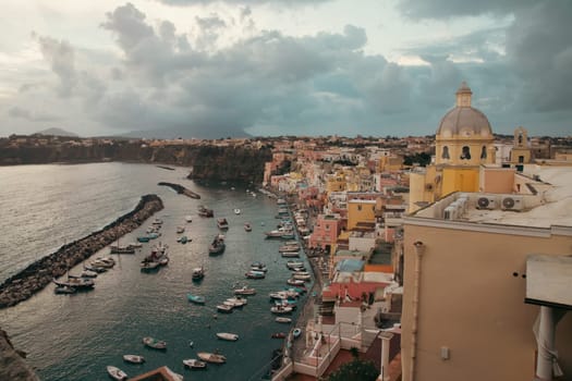 View of the Port of Corricella with lots of colorful houses after sunset in Procida Island, Italy.
