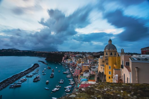 View of the Port of Corricella with lots of colorful houses after sunset in Procida Island, Italy.