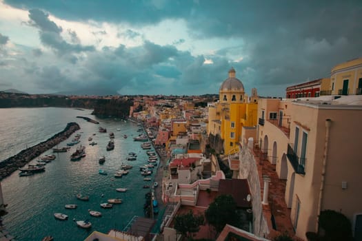 View of the Port of Corricella with lots of colorful houses after sunset in Procida Island, Italy.