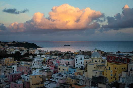 View of the Port of Corricella with lots of colorful houses in the sunset in Procida Island, Italy.