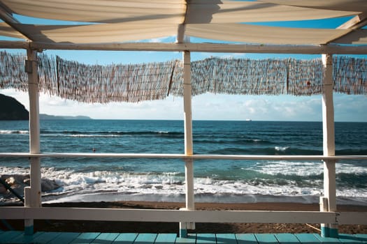 Cozy terrace on the beach, idyllic view of the seashore. Tropical summer vacation concept.
