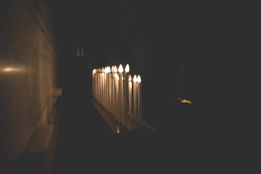 Many burning candles with shallow depth of field in a church