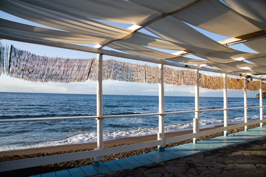 Cozy terrace on the beach, idyllic view of the seashore. Tropical summer vacation concept.