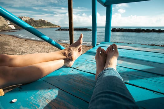 Closeup photo of women's legs on the blue wooden pier over the sea, summer vacation concept
