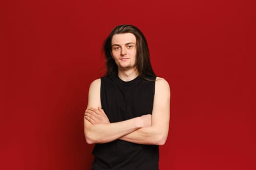 Studio portrait of young handsome man with long black hair over red background