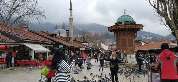 Sarajevo, Bosnia and Herzegovina, March 8, 2020, people walk the central streets of Sarajevo feeding pigeons. Bascarsija and square. Islamic landmarks and tourist sites. Birds walk on the pavement.