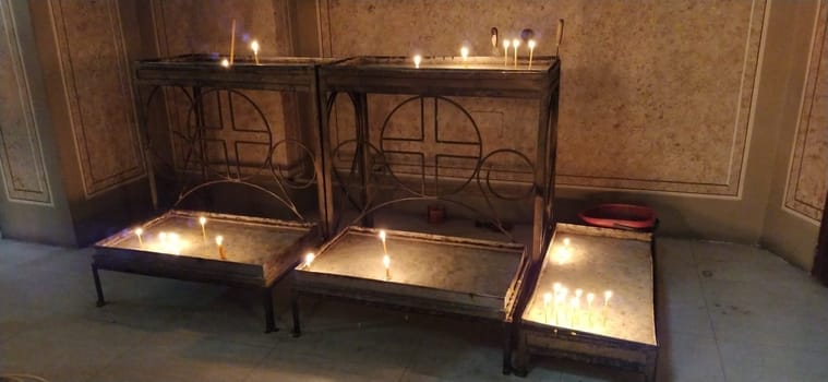 burning candles in the church on metal tables. Ignited symbols of the memory of the departed.