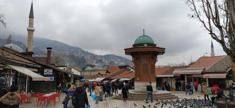 Sarajevo, Bosnia and Herzegovina, March 8, 2020, people walk the central streets of Sarajevo feeding pigeons. Bascarsija and square. Islamic landmarks and tourist sites. Birds walk on the pavement.