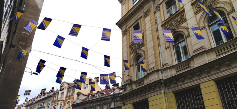 Sarajevo, Bosnia and Herzegovina, 8 March 2020. Streets of Sarajevo with flags. Historical and tourist center of the city. Bottom up view. Facades of old houses, festive decorations