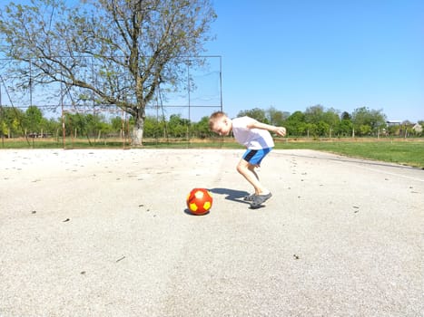 Sremska Mitrovica, Serbia. June 6, 2020. Sports games on the sports ground in the summer. The child plays with a ball. Schoolboy boy playing basketball during summer holidays