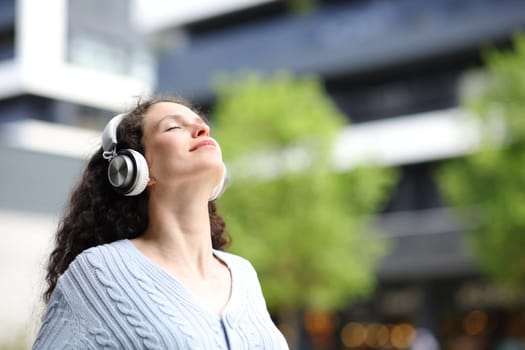 Woman breathing and meditating with headphones in the street
