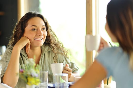 Two friends talking at breakfast drinking coffee in a restaurant