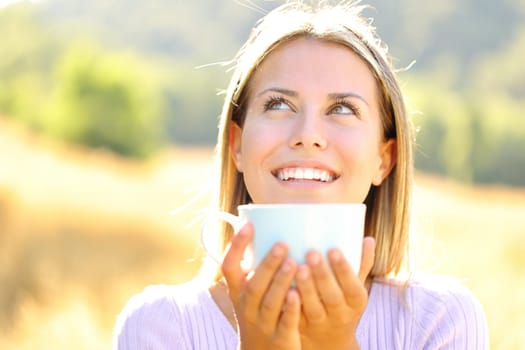 Happy teen laughing drinking coffee in nature looking above