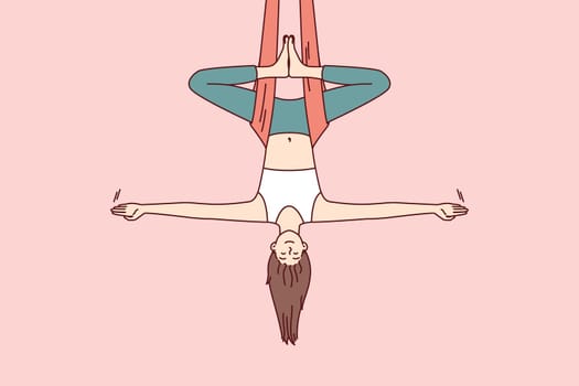 Woman doing aerial yoga hangs upside down in hammock and keeps balance with arms at sides. Girl during workout in yoga studio meditates enjoying practices that cause harmony and get rid of nerves