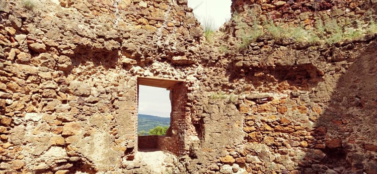 Ruins of an old fortress in Vrdnik, Sremska Mitrovica, Vojvodina, Serbia. Ancient stone walls with mountain ranges in the background. Tourist sights. Embrasure or window for observation and defense.