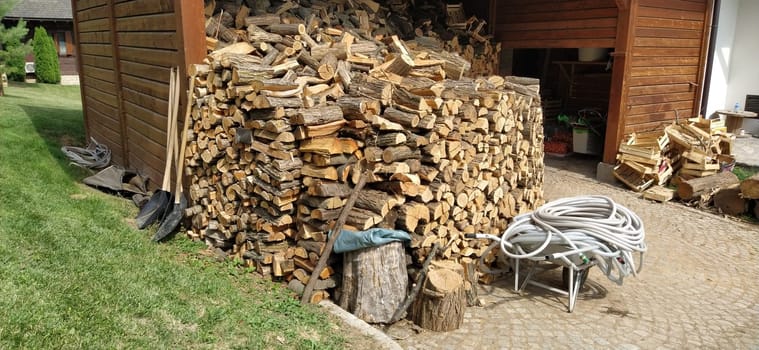 Firewood in the barn. Around the utility room are wooden firewood, rubber hoses, household utensils. Restaurant backyard in ethno style. Wooden architecture.