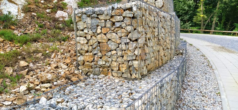 engineering protection against landslide and landslide processes in road construction. Protection against collapse of soil and stones on the road. Stones placed in metal frames.