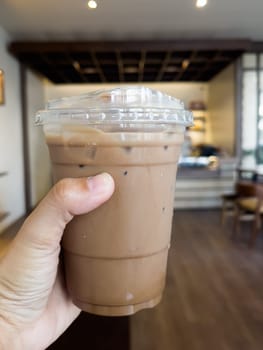 Hand holding glass of iced coffee mocha, stock photo