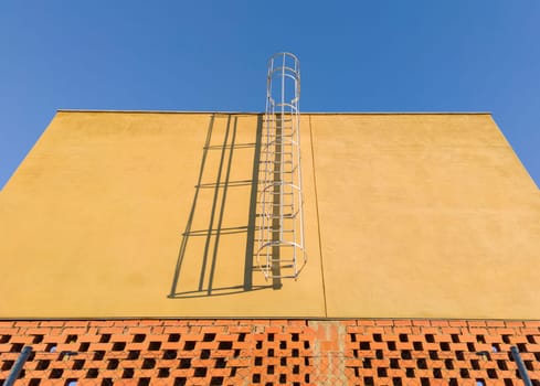 fixed Service ladder installed on a commercial premises under construction. Blue sky background