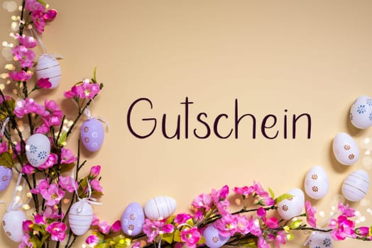 German Text Gutschein Means Voucher On Beige Background. Pink And Purple, Shiny And Bright Spring Flower Arrangement With Easter Egg Decoration.