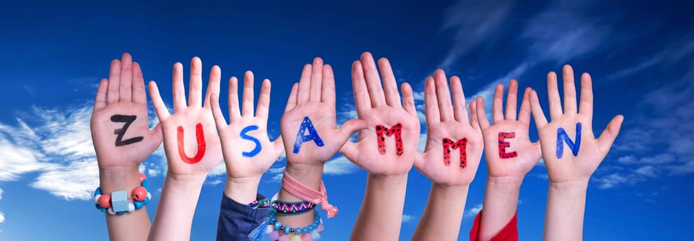 Children Hands Building Colorful German Word Zusammen Means Together. Blue Sky As Background