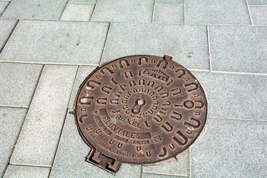 Costa Adeje, Tenerife, Spain August 12, 2022 - Manhole cover in a sidewalk