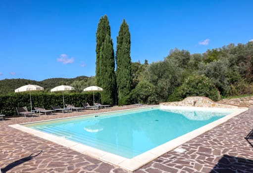 A swimming pool on the Montemassi hillside surrounded by cypresses and oleanders n the province of Grosseto. Italy