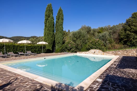 A swimming pool on the Montemassi hillside surrounded by cypresses and oleanders n the province of Grosseto. Italy
