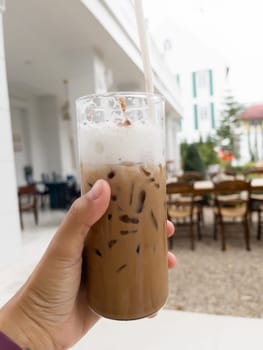 Hand holding glass of iced coffee mocha, stock photo
