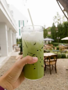 Hand holding glass of iced matcha green tea, stock photo