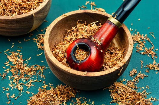 Fragrant smoking tobacco and a smoking tube or pipe on the table.