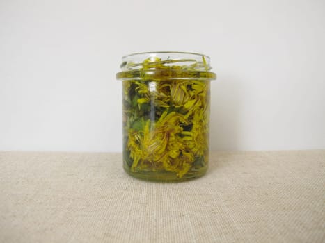 Tincture with dandelion flowers in a glass jar