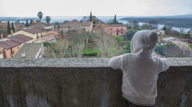 Granadilla village. Hooded child boy enjoying an aerial view from castle. Extremadura, Caceres, Spain