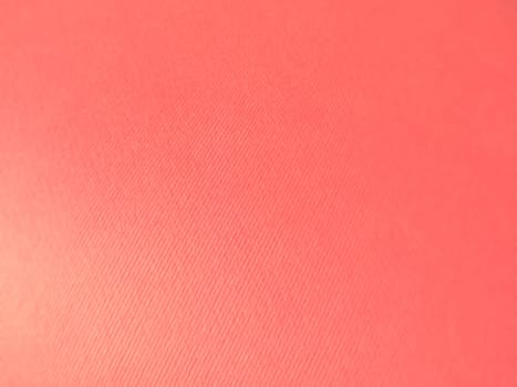 Abstract pink background with texture. Close-up of paper surface with light and color gradient. Side lighting. Soft pastel peach or ruddy tone backdrop