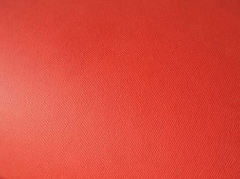 Abstract red background with texture. Close-up of paper surface with light and color gradient. Side lighting. Bright crimson backdrop.