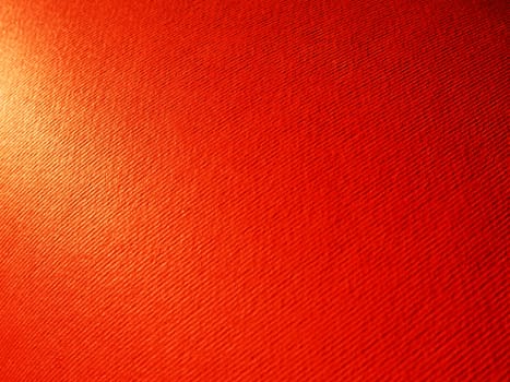 Abstract red background with texture. Close-up of paper surface with light and color gradient. Side lighting. Bright crimson backdrop.