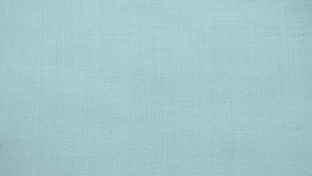 texture of natural light green or blue fabric close-up. The texture of the fabric is made of natural cotton or linen textile material. Green canvas background. Smooth surface of mint-colored fabric.